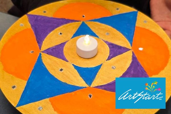 Geometric art in orange, blue and purple on a circular wooden panel with a tea light in the middle