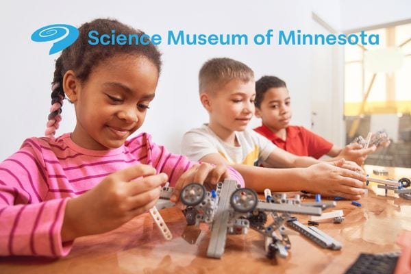 Children at table building miniature moving vehicles with plastic blocks