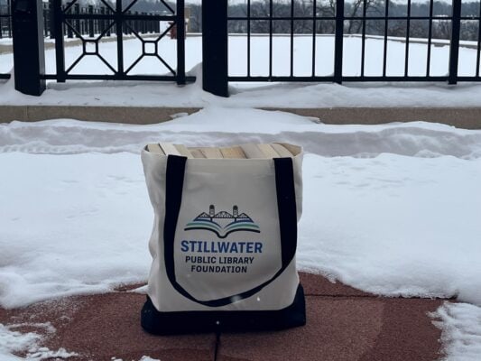 Foundation canvas tote big filled with books and outside on library terrace surrounded by snow