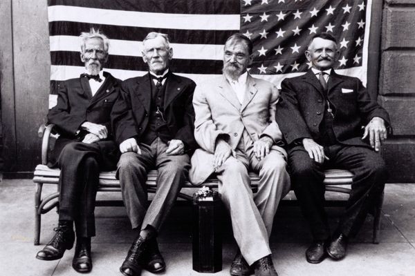 4 Civil War vets seated in front of an American Flag