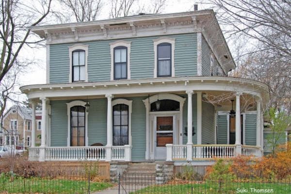 Two-story historic home with light blue-green paint with cream trim