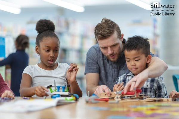 Two children and an adult constructing with toys